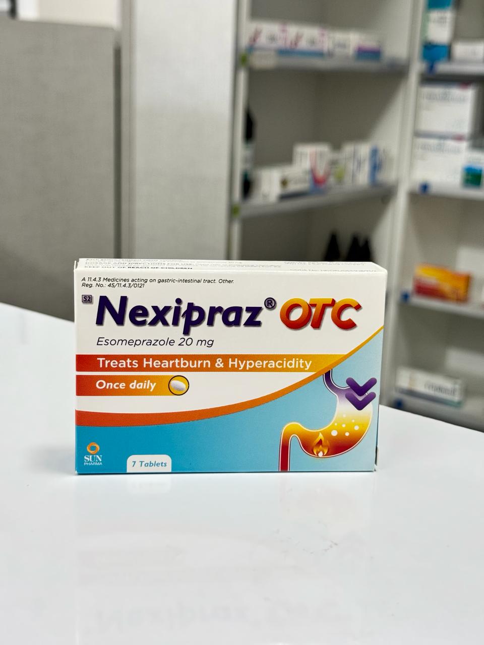 Nexipraz OTC medication box on a surface with a blurred background of shelves.